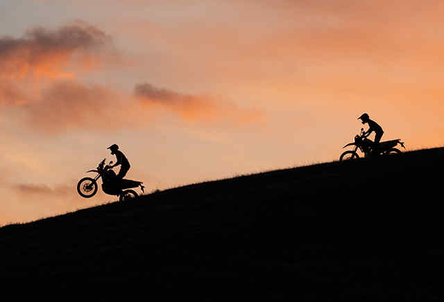 Due motociclette Honda serie 300 scendono da una collina al tramonto