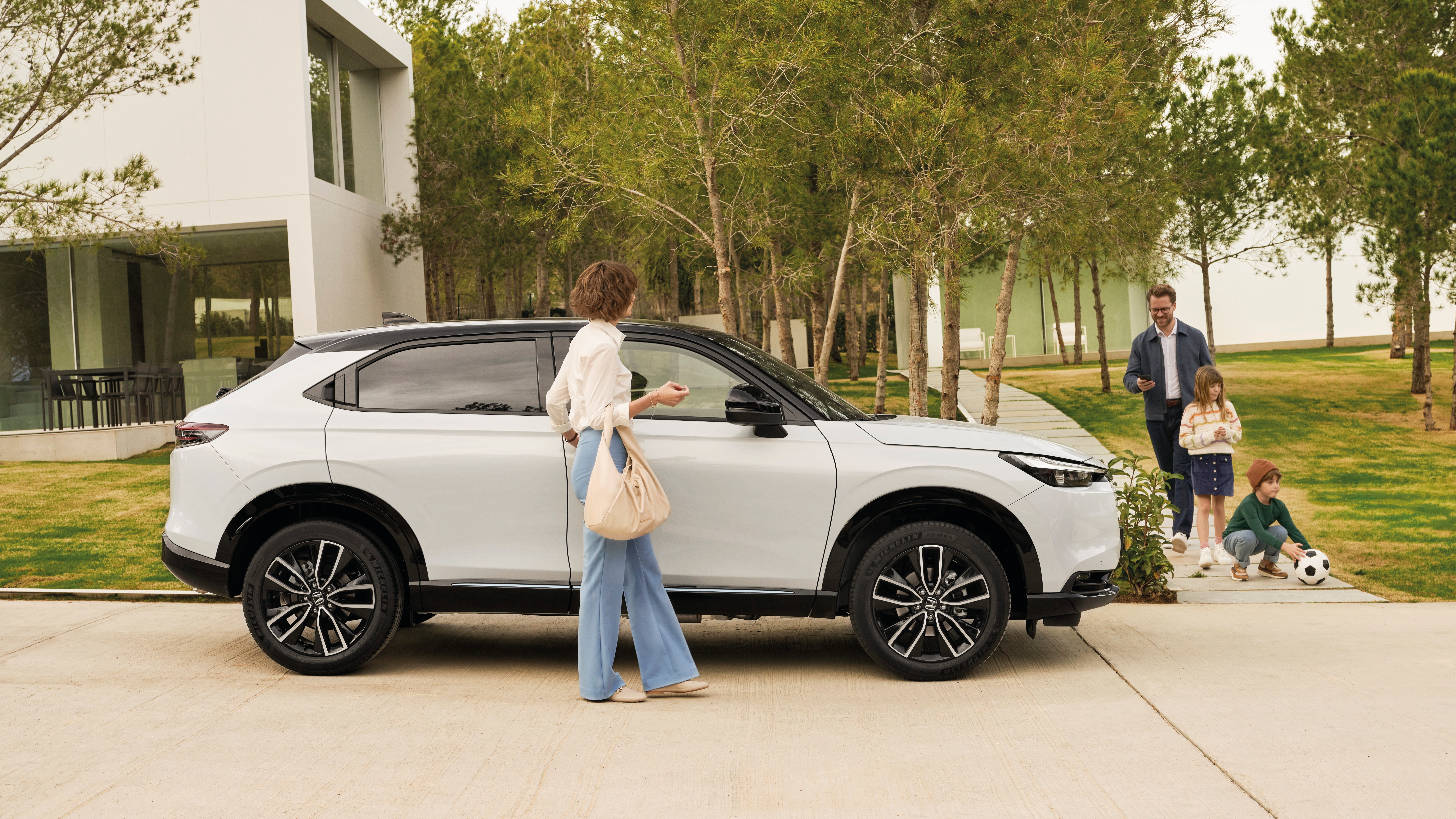 Una famiglia di quattro persone in procinto di salire sul loro SUV ibrido Honda