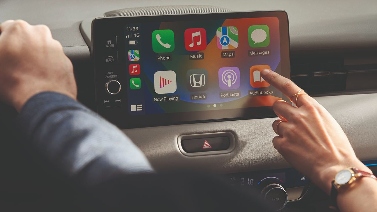 Una mano che sta per cliccare sullo schermo del cruscotto di un'auto Honda