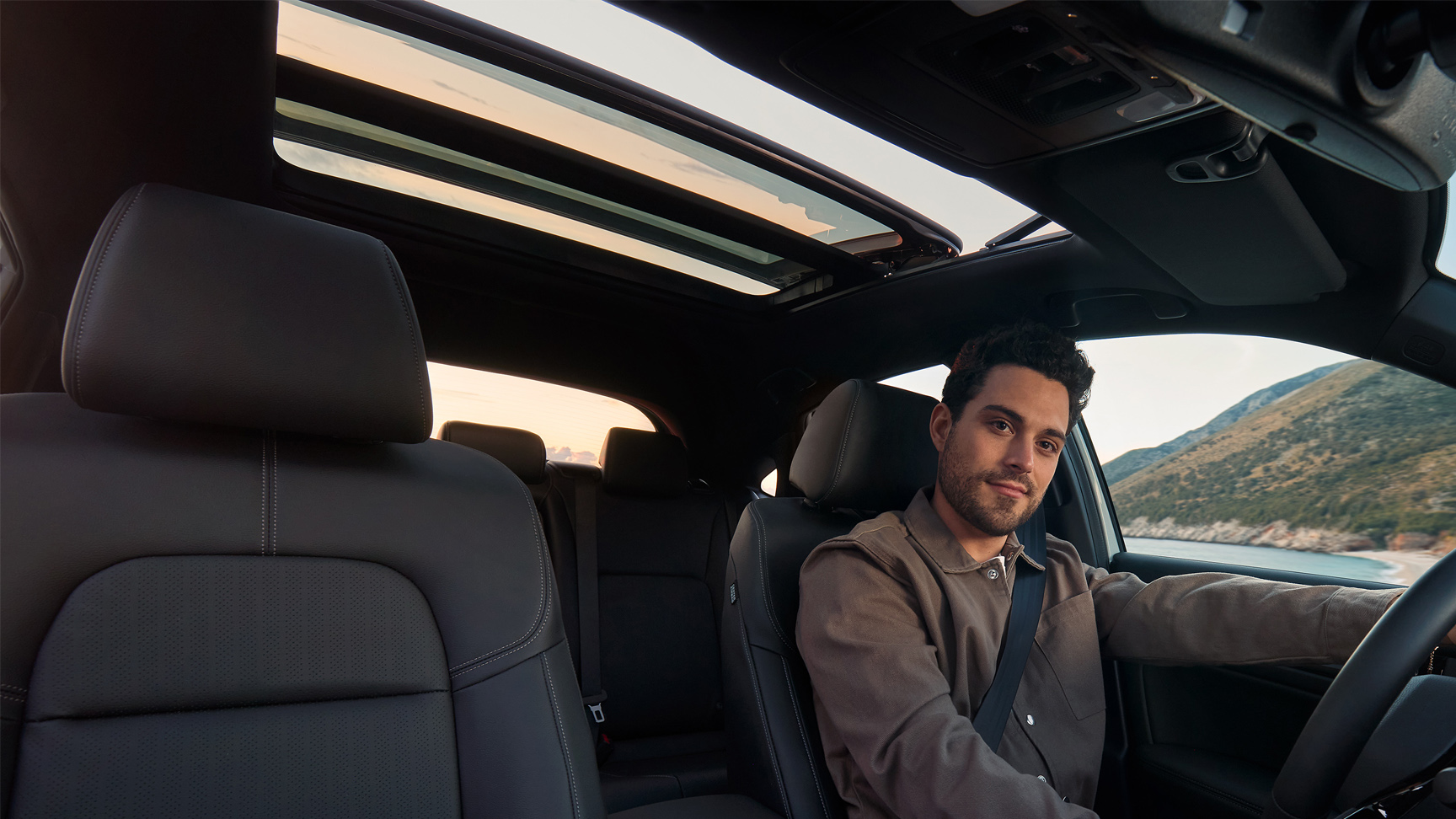 Ripresa dell'interno della Civic Hybrid con un uomo alla guida incentrata sul tetto panoramico aperto.
