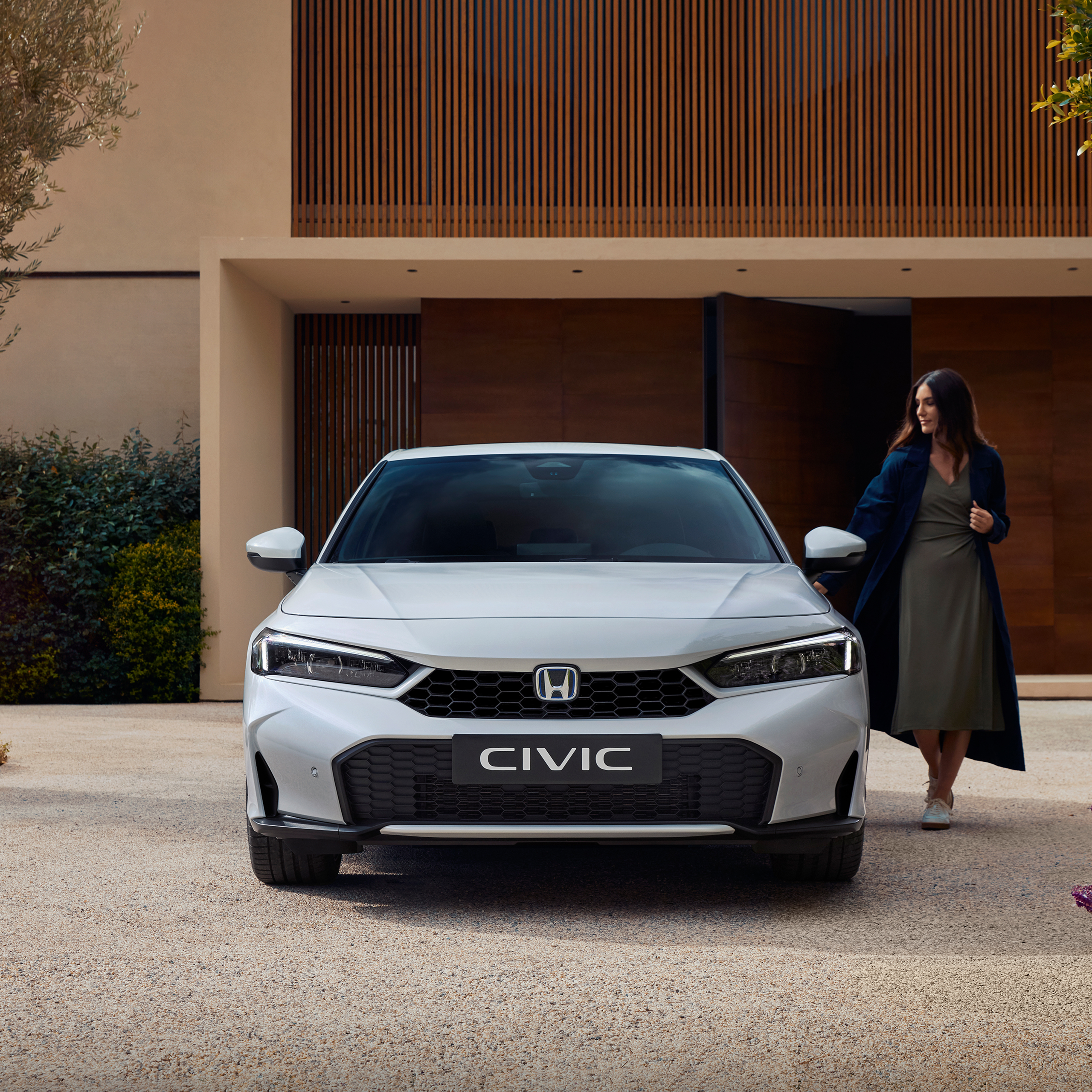 Ripresa frontale di una Civic Hybrid, con una donna che ne apre la portiera.