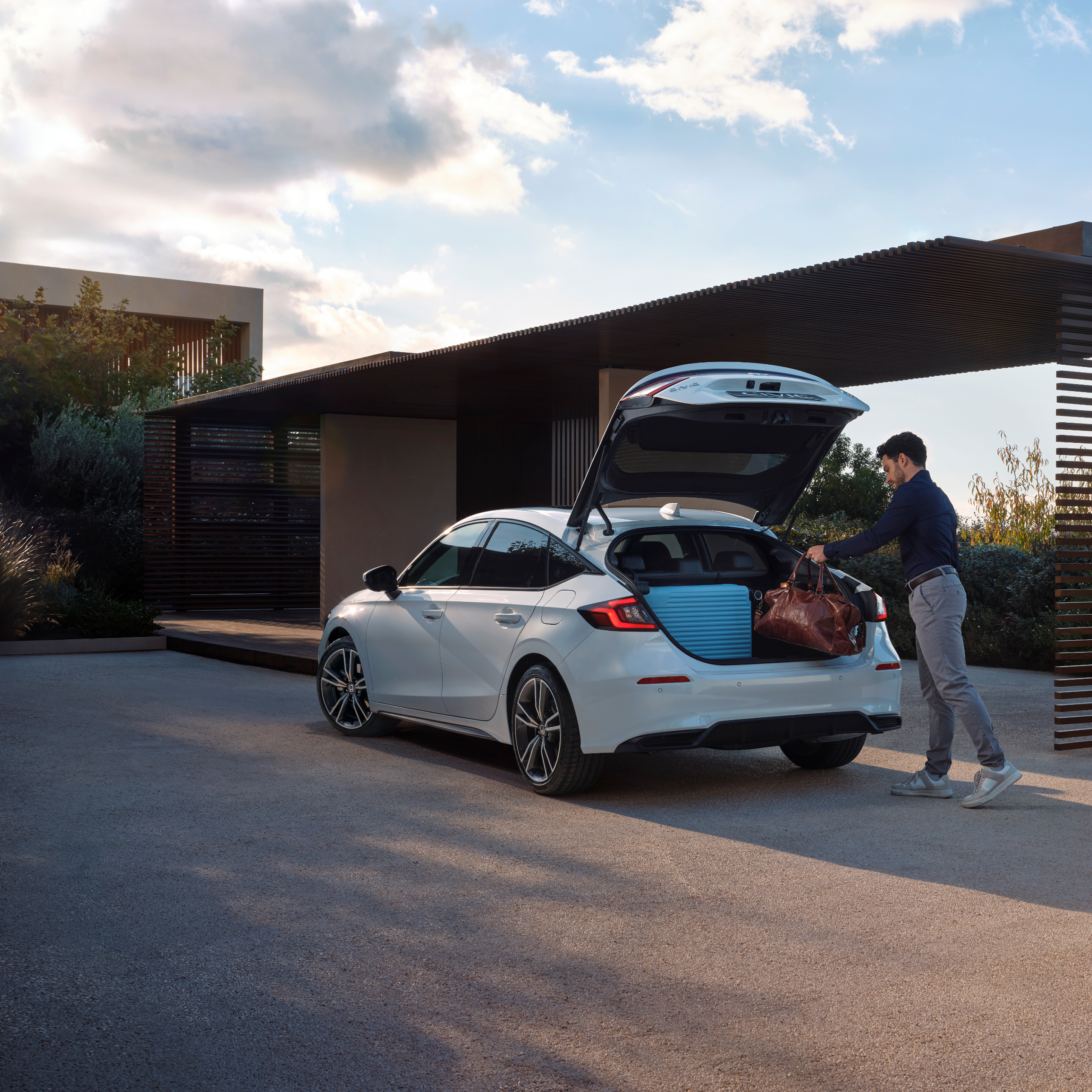 Una persona che mette i bagagli nel bagagliaio della Civic Hybrid.