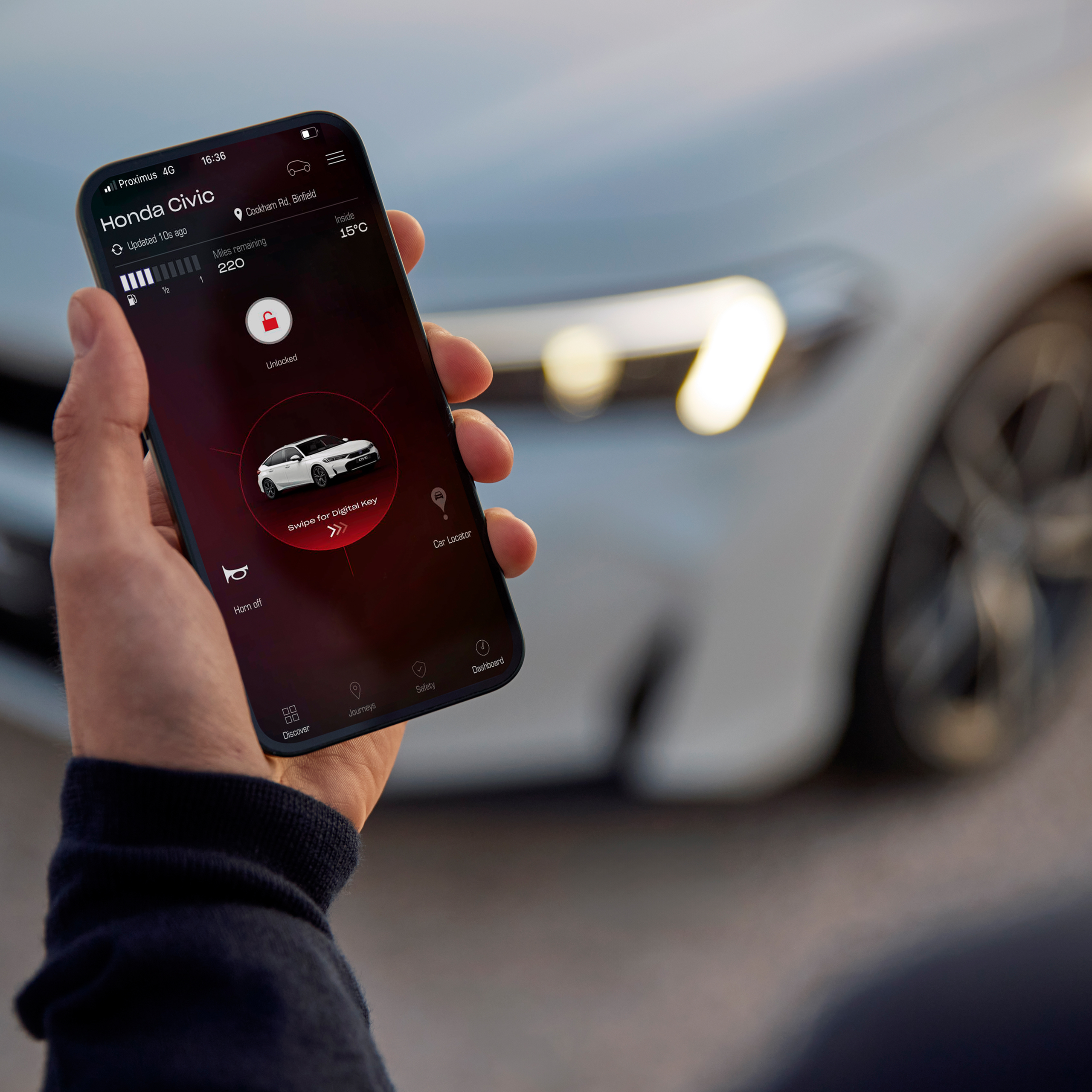 Una persona che tiene in mano uno smartphone con My Honda+ app.