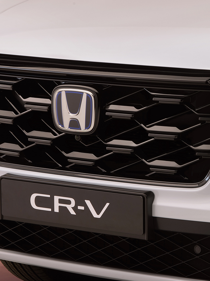 Primo piano della griglia anteriore della Honda CR-V, con motivo a nido d'ape nero, il logo Honda al centro e il nome del modello CR-V visibile nella parte inferiore.