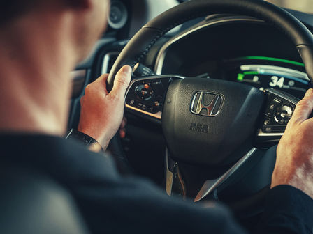Primo piano di un modello in macchina al volante dell'Honda CR-V Hybrid.