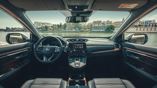 Primo piano del cruscotto interno di Honda CR-V Hybrid ambientato in una strada.