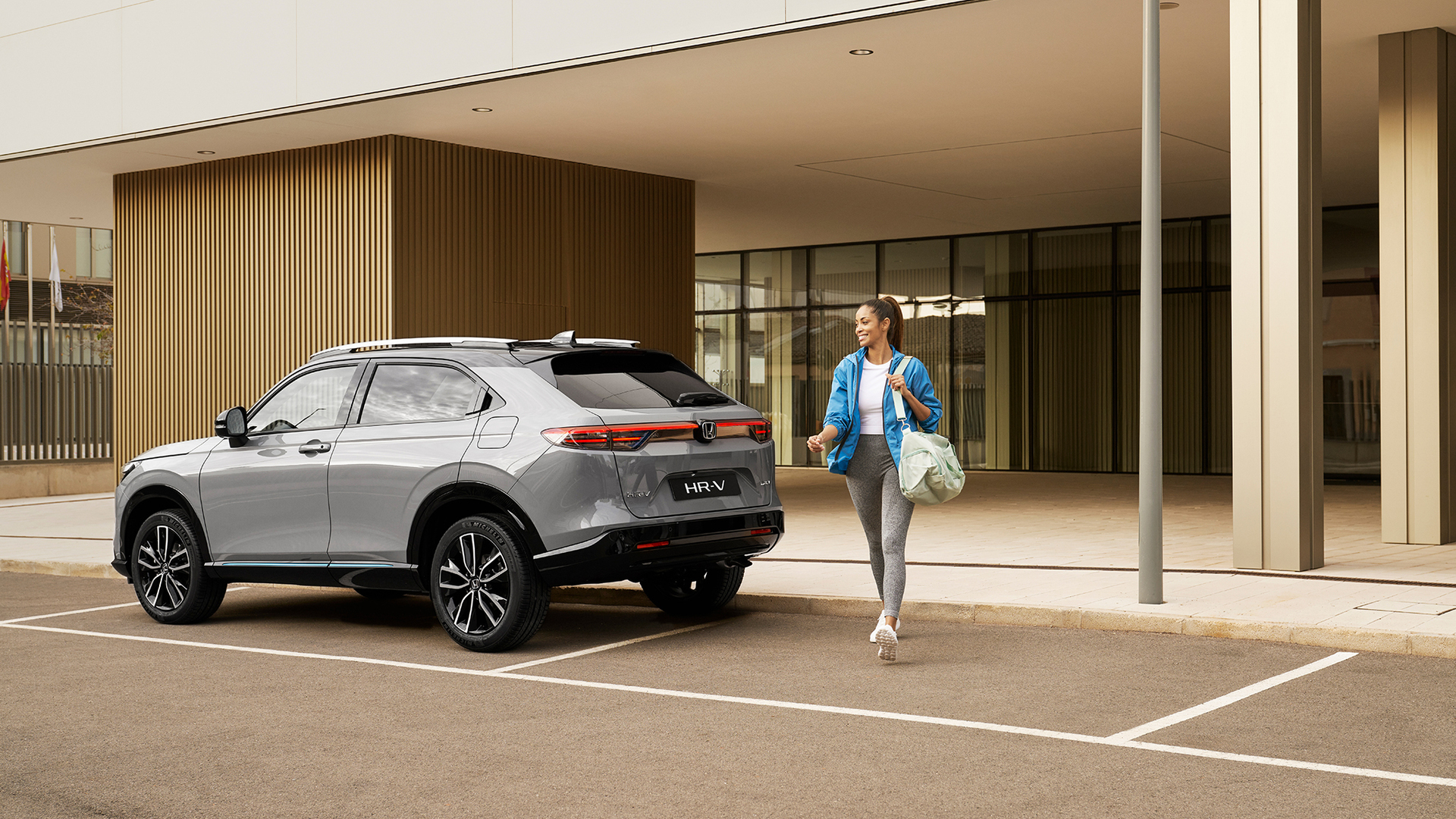 Donna che cammina a lato di un HR-V parcheggiato.