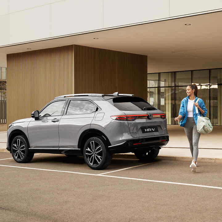 Donna che cammina a lato di un HR-V parcheggiato. 