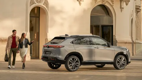 Vista alterale di Honda HR-V fuori da un hotel con una coppia che passa accanto. 
