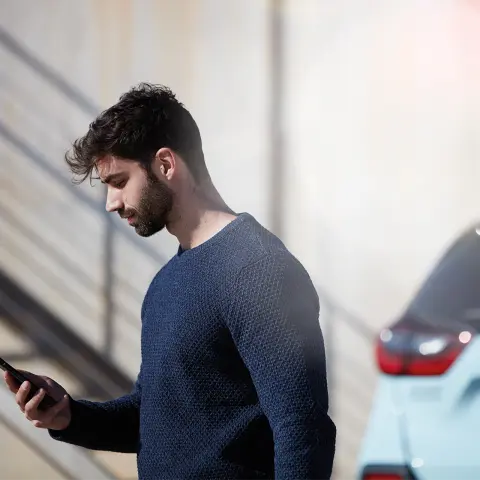 Uomo in piedi accanto a Jazz Crosstar mentre utilizza l'app My Honda Plus.