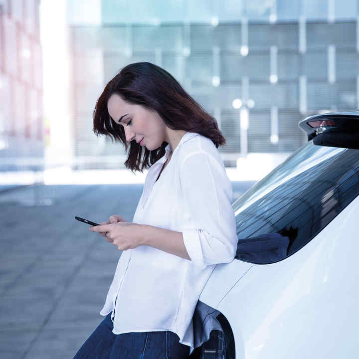 Donna appoggiata alla parte posteriore della Honda e mentre guarda il telefono