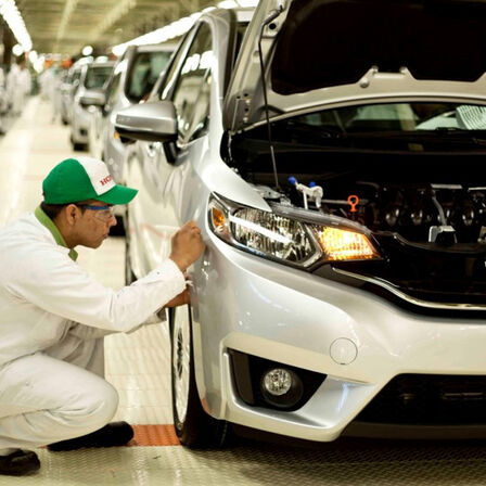 Tecnico Honda che lavora su un'auto in fabbrica.