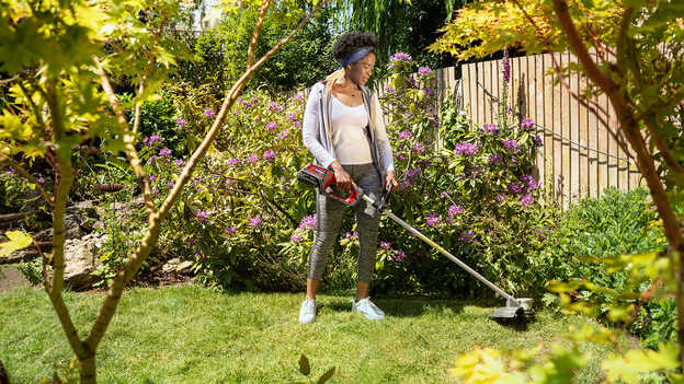 Femme dans un jardin utilisant une débroussailleuse à batterie Honda.