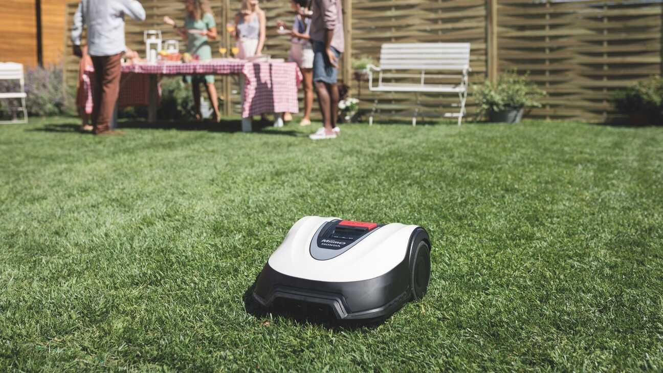 Vista frontale di tre quarti di Honda Miimo in giardino con modelli e mobili sullo sfondo.
