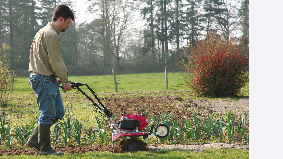 Mini-motozappa, rivolta a destra, utilizzata da un operatore, luogo di utilizzo: giardino. Motozappa Honda FG 220