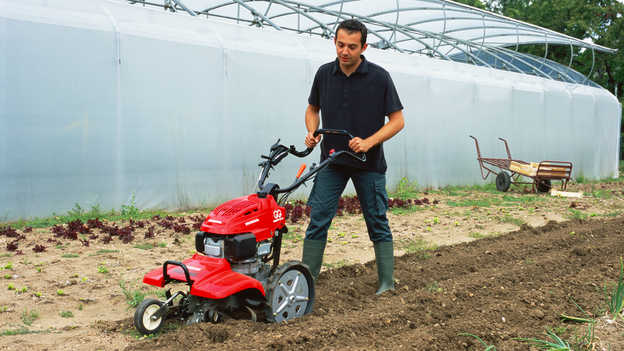 Vista anteriore della motozappa controrotante che lavora il terreno. 