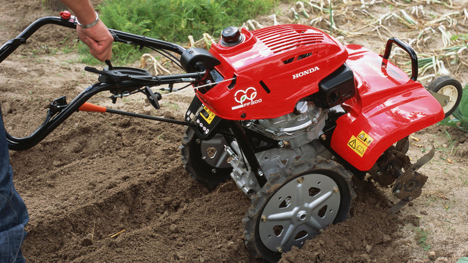 Primo piano di una motozappa controrotante, con dettaglio delle stegole regolabili, luogo di utilizzo: giardino.