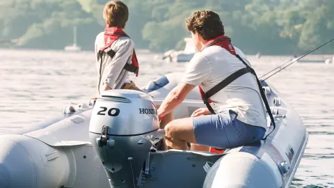 Due uomini su una barca Honwave con motore BF20 in un lago.
