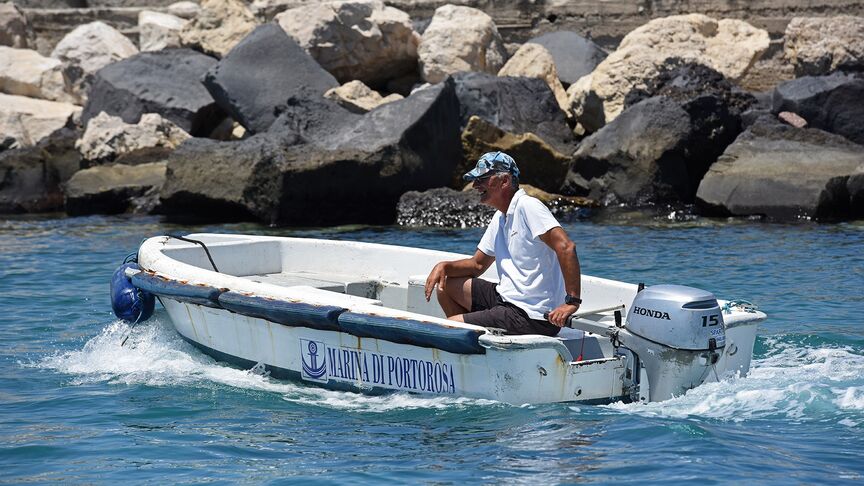 Uomo su una barca con motore BF15 in zona costiera. 