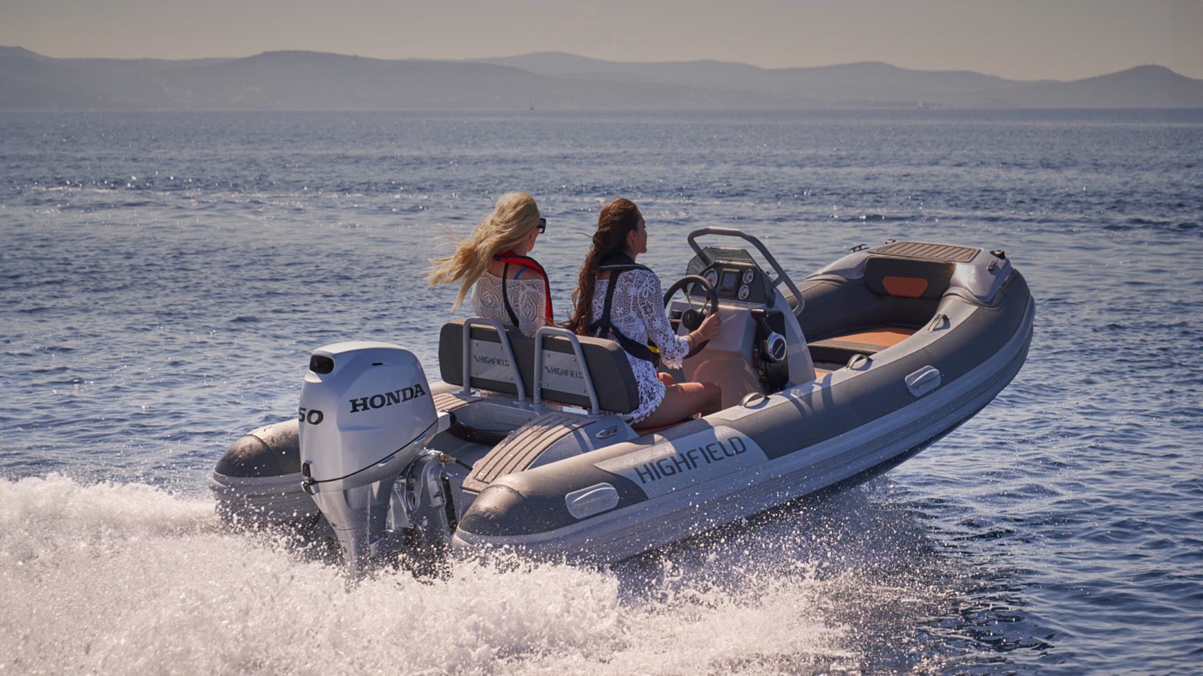 Due modelli su una barca Highfield con motore Honda BF50 in mare.