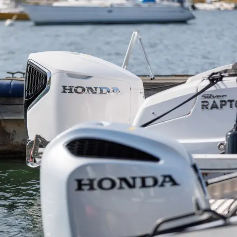 Primo piano dei motori Honda sul retro delle barche in un ambiente acquatico. 