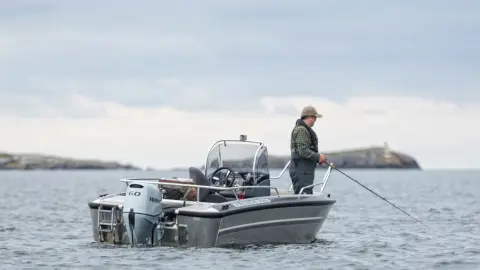 Uomo che pesca su una barca con motore Honda BF60.