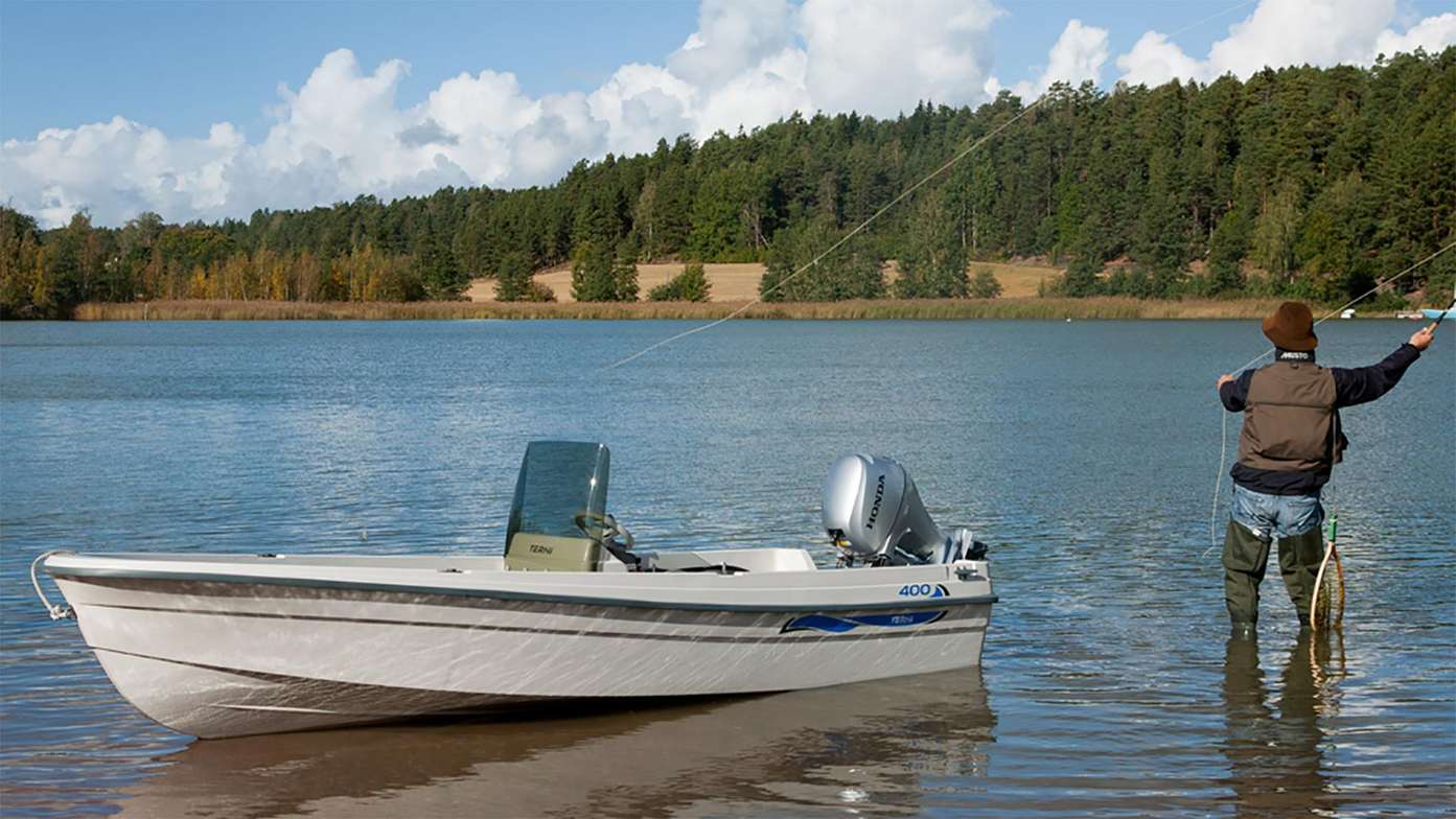 Uomo che pesca accanto a una piccola barca con un motore fuoribordo Honda