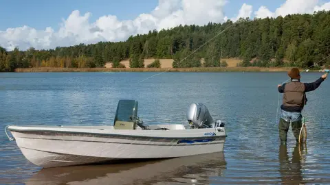 Pescatore nel lago con barca nelle vicinanze che mostra il motore BF8-10.