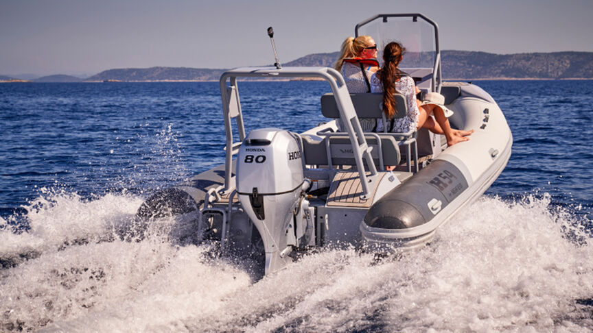 Modello nell'atto di sterzare una barca con motore BF80-100 in mare.