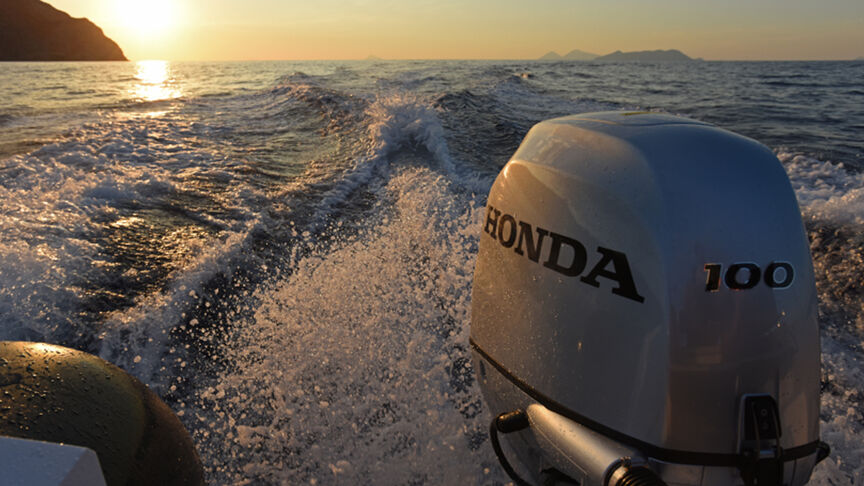 Modello nell'atto di sterzare una barca con motore BF80-100 in mare.