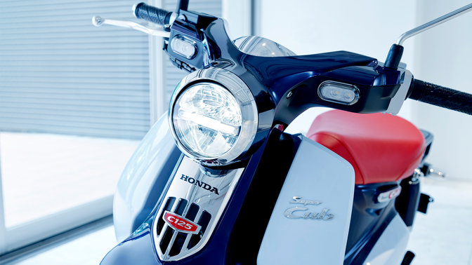 Honda Super Cub parcheggiata in un ambiente dall'aspetto moderno.