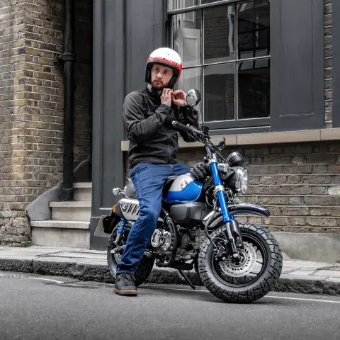 Honda Monkey 125 con pilota parcheggiata sul lato della strada