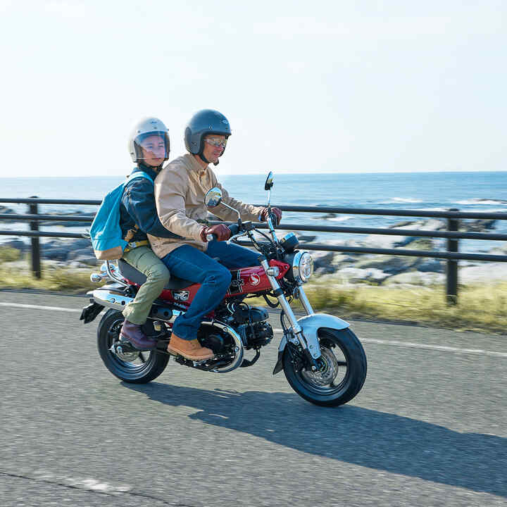 Honda Dax 125 su una strada costiera con pilota e passeggero