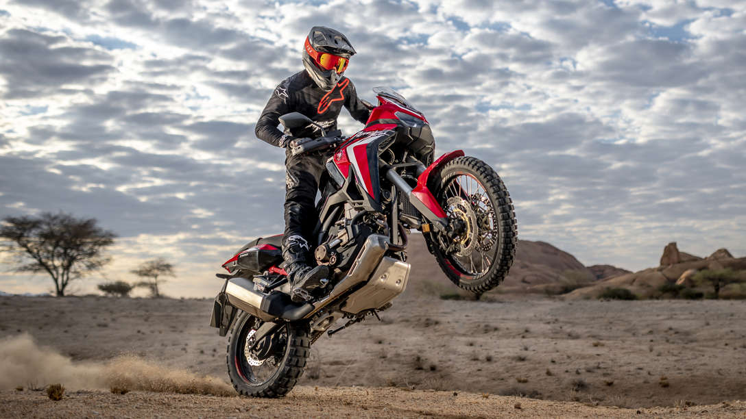 Honda Africa Twin, inquadratura anteriore destra di tre quarti, impennata in un paesaggio desertico