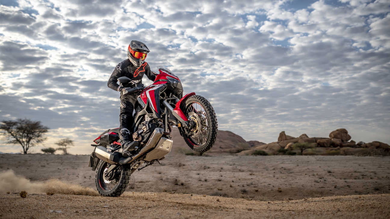 Honda Africa Twin, inquadratura anteriore destra di tre quarti, impennata in un paesaggio desertico