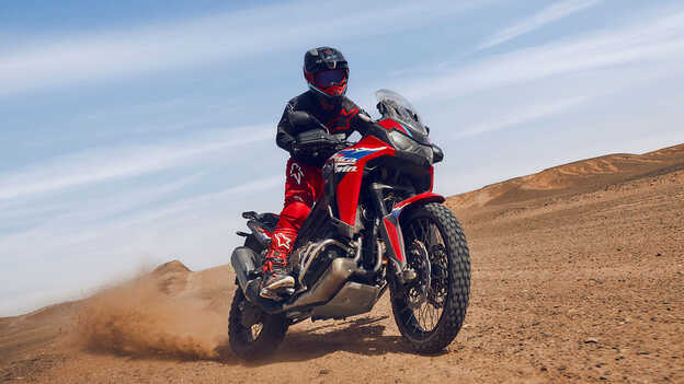 Modello su moto CRF1100L Africa Twin in una località desertica.