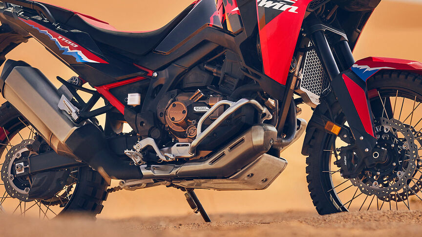 Modello in sella a una moto CRF1100L Africa Twin in un luogo desertico.