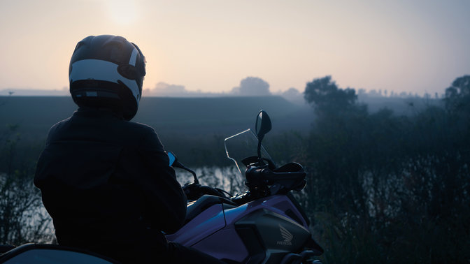 Pilota in sella a una Honda NC750X, in un ambiente rurale.