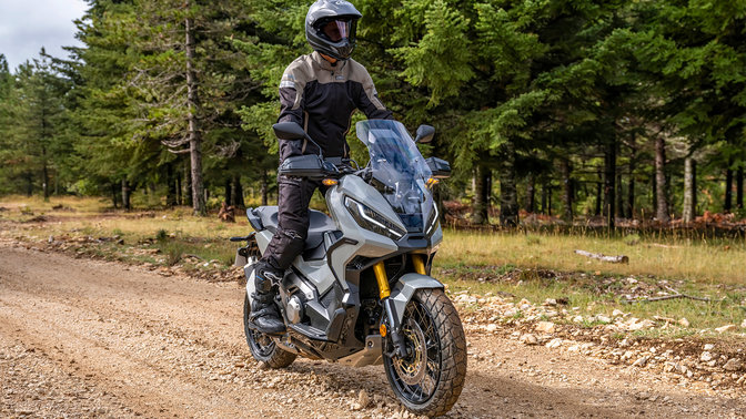 Honda X-ADV, vista di tre quarti anteriore destra, con guidatore, su strada nella foresta