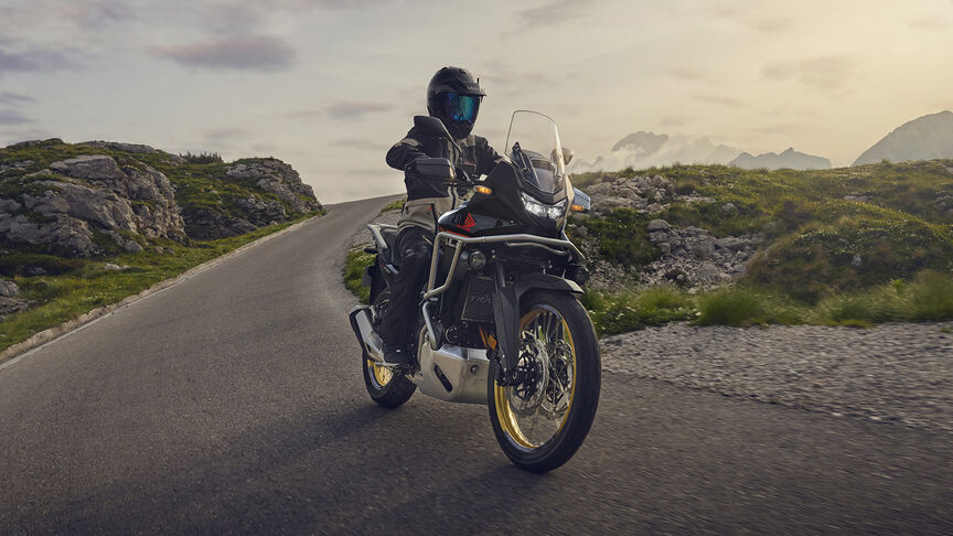 Pilota alla guida di XL750 Transalp in un luogo boschivo.
