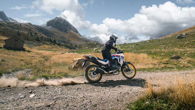 Immagine dinamica posteriore di Transalp con pilota sulla ghiaia