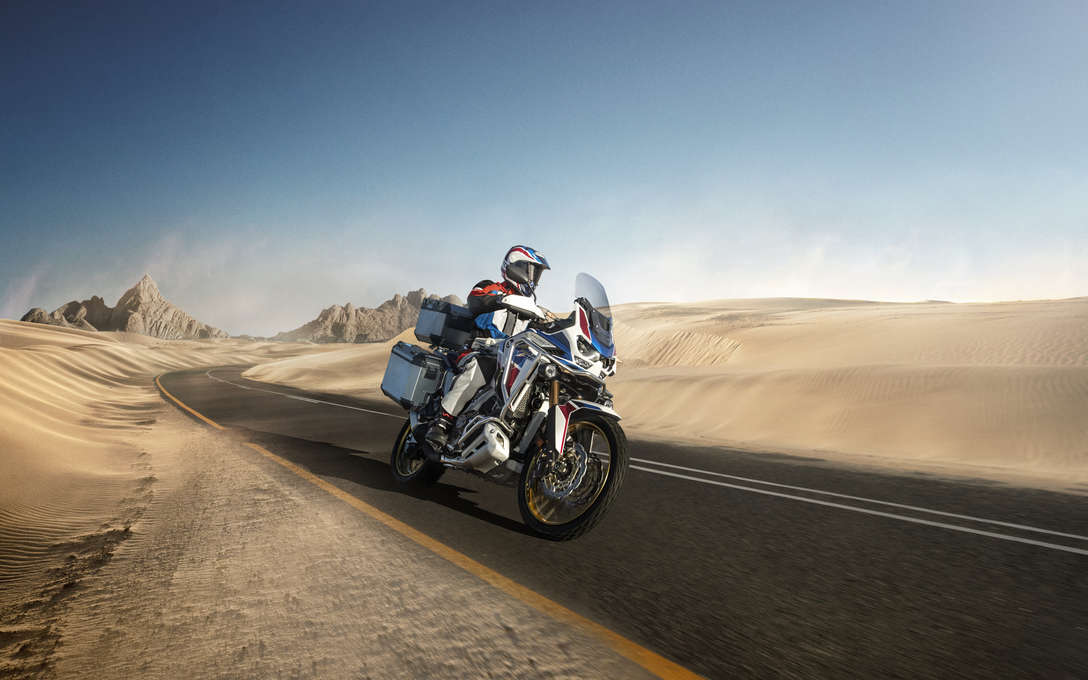 Honda Africa Twin Adventure Sports, inquadratura anteriore destra di tre quarti, guidata su una strada in un paesaggio desertico