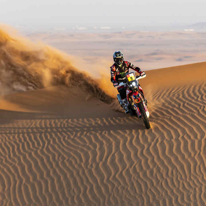 Pilota su una Honda Dakar tra le dune del deserto. 