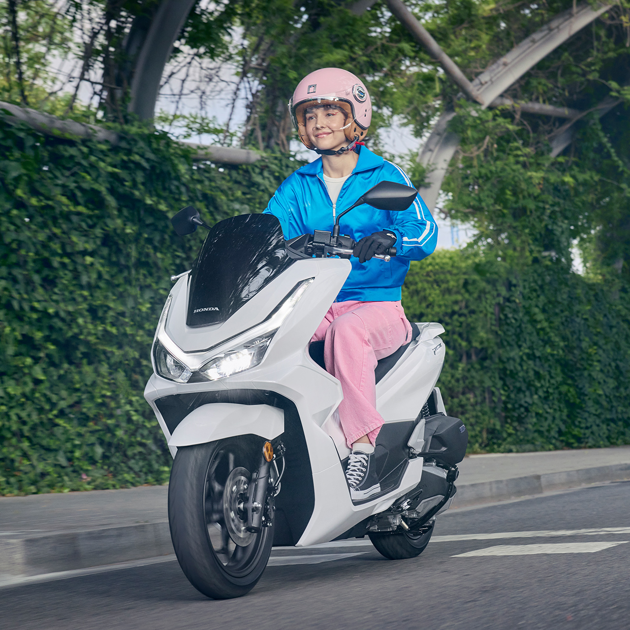 Modello alla guida di uno scooter PCX125 in un contesto urbano