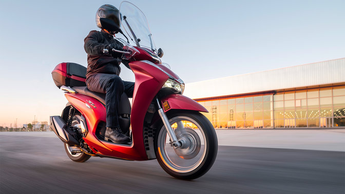 Honda SH350i, vista anteriore di tre quarti destra, con guidatore, su strada, moto rossa