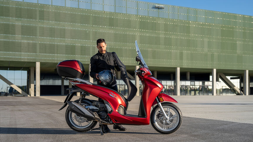 Honda SH350i, vista anteriore di tre quarti destra, con guidatore, su strada, moto rossa