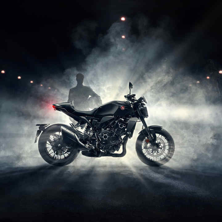 Honda CB1000R - Black Edition - lato destro, guidatore dietro alla moto con nebbia di notte, moto nera
