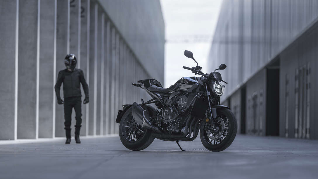 Honda CB1000R Black Edition, uomo in piedi accanto alla moto su una strada tra gli edifici