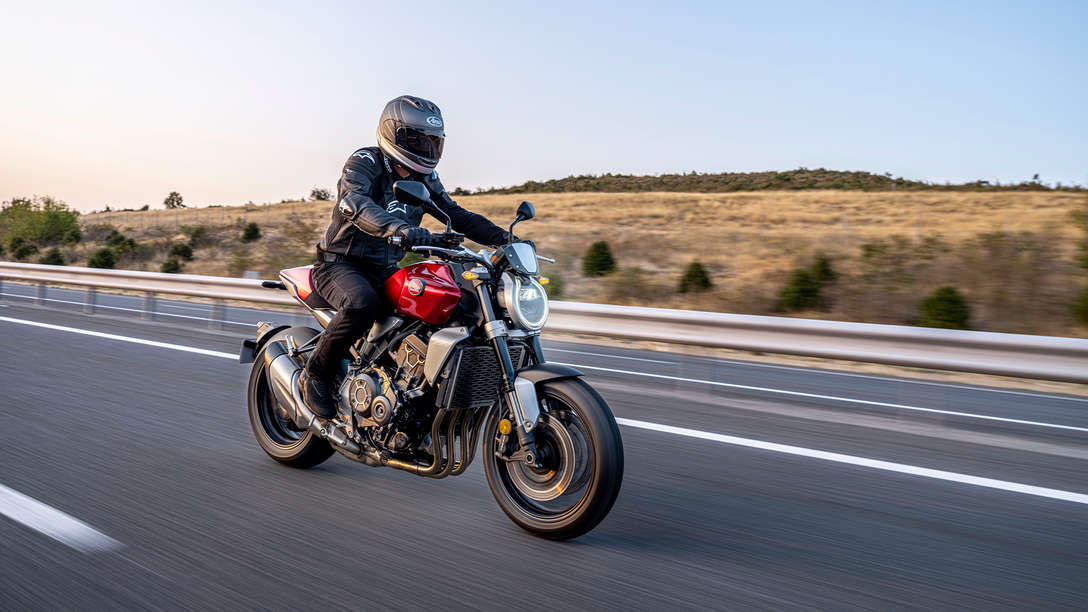 Honda CB1000R, vista di tre quarti posteriore destra, con un guidatore, moto rossa, su strada