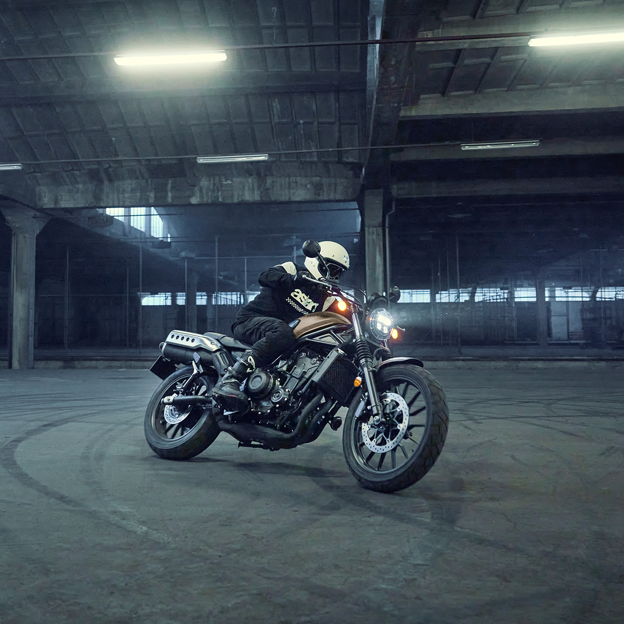 Modello/a alla guida di una moto Honda CL500 in un parcheggio.